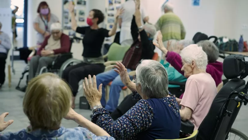 Des personnes âgées en fauteuil roulant font des exercices en présence d'une soignante