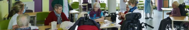 Un groupe de personnes âgées en fauteuils roulants participe à une animation