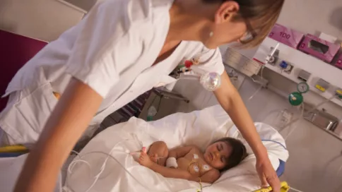 Une infirmière s'occupe d'un bébé endormi dans un lit adapté