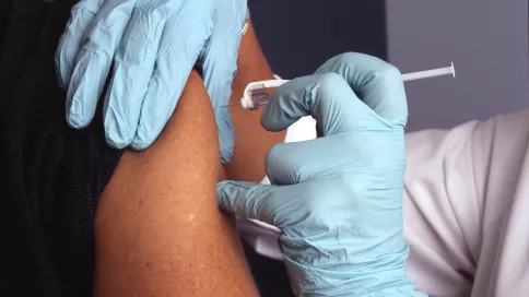 une personne reçoit un vaccin dans l'épaule