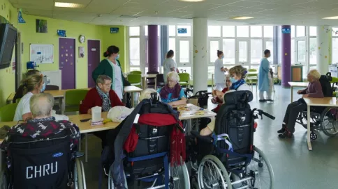 Un groupe de personnes âgées en fauteuils roulants participe à une animation